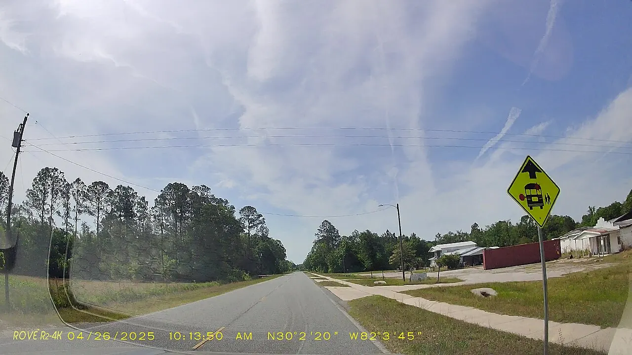 A School Bus Stop Ahead warning sign beside eastbound County Road 225 in Bradford County, Florida, seen from a car