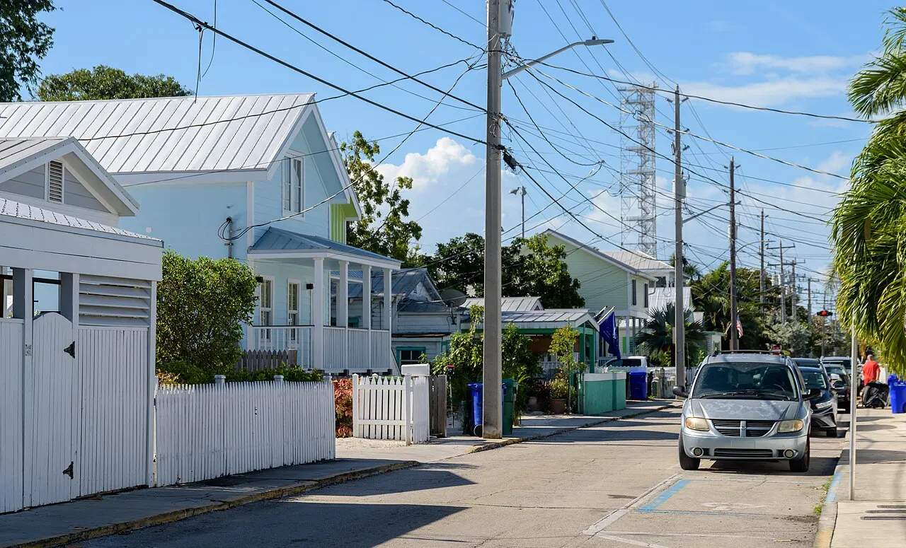 A residential street lined with houses and parked cars in Key West, Florida