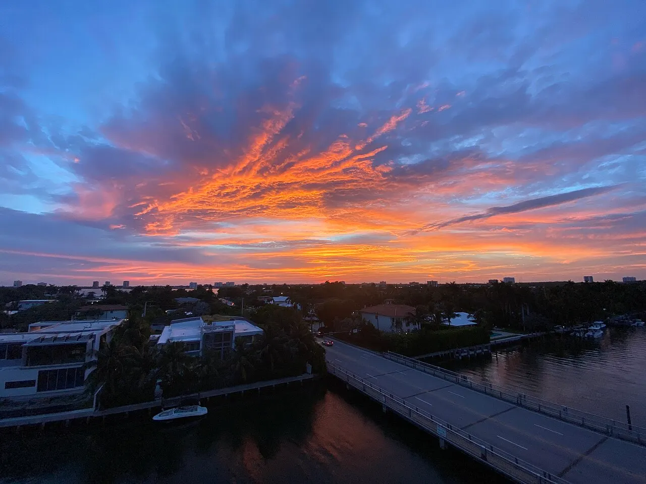 A two-lane road bridge over a waterway in Miami, Florida, under a dusk sky