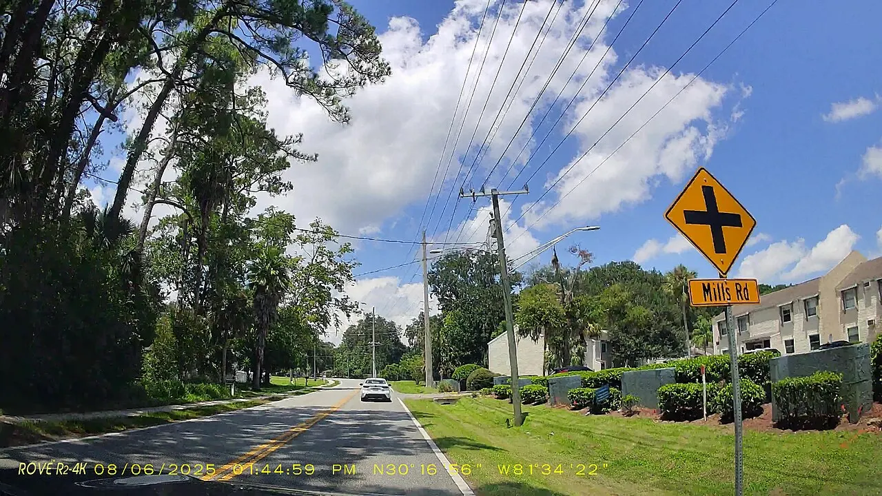 Yellow Cross Road warning sign above a Mills Rd street name plaque on westbound Hogan Road in Jacksonville, Florida