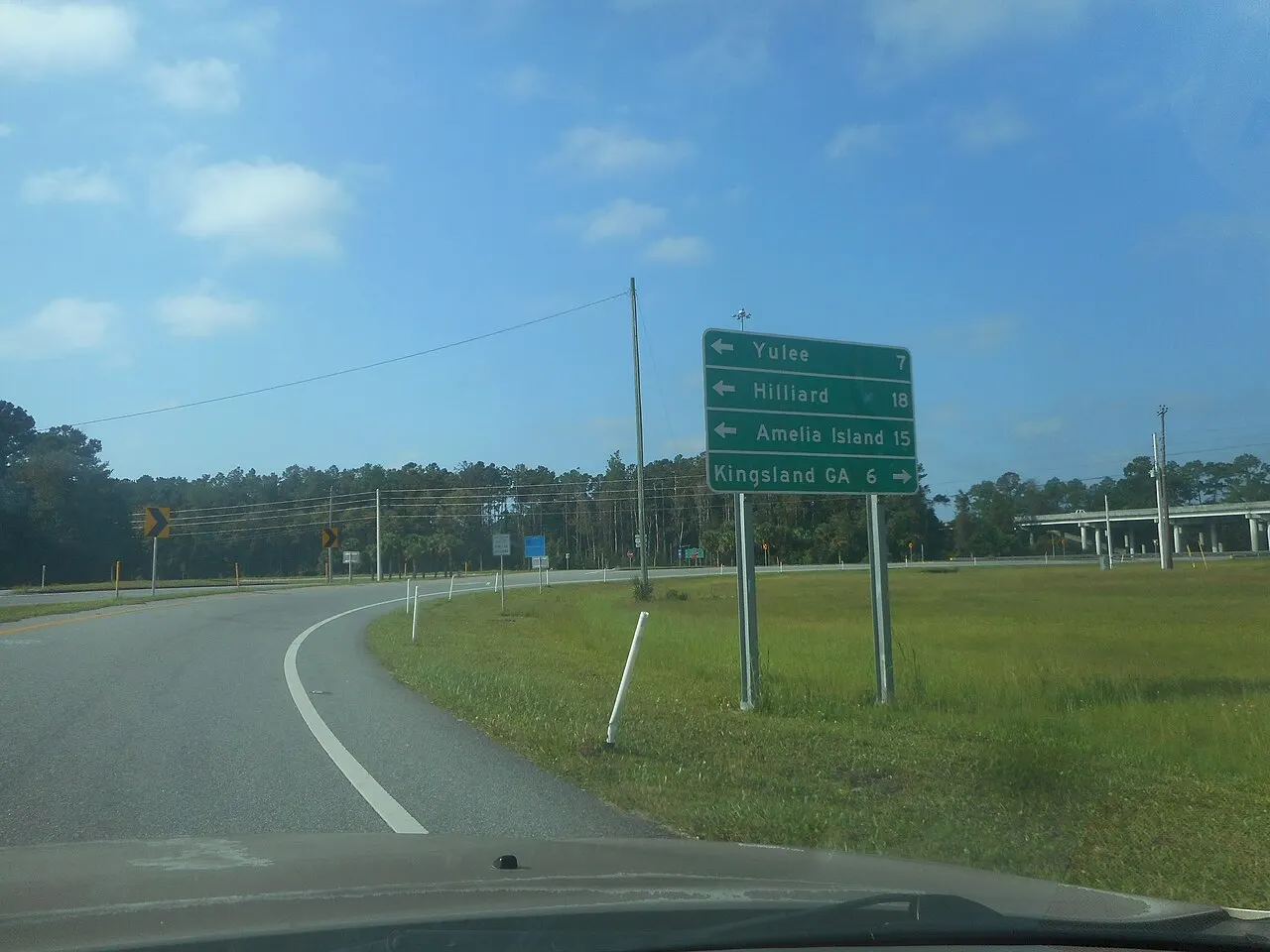 Green destination sign listing Yulee, Hilliard, Amelia Island and Kingsland GA with arrows and mileages beside an off-ramp