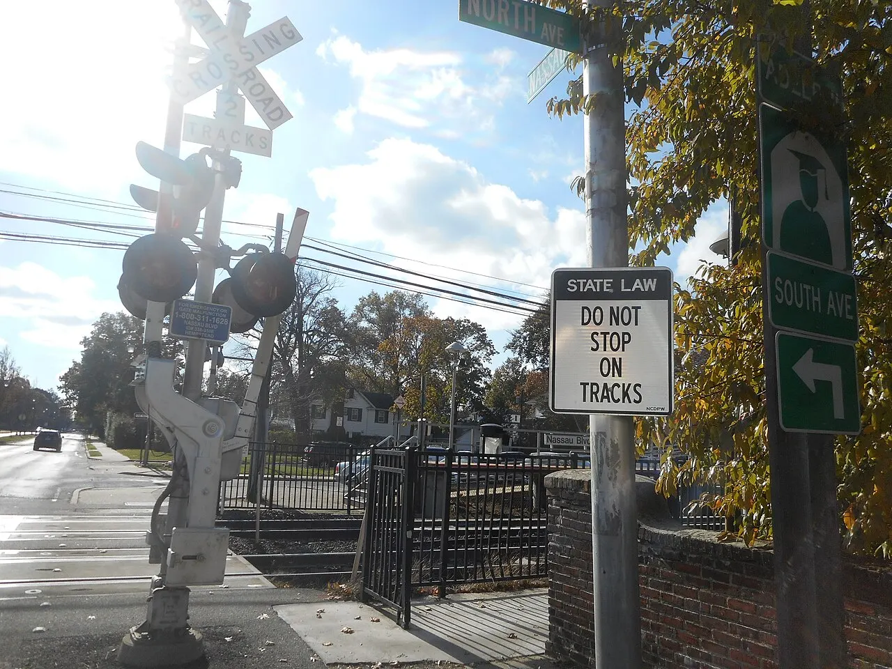 Do Not Stop On Tracks sign with a State Law header beside a railroad crossbuck and flashing lights
