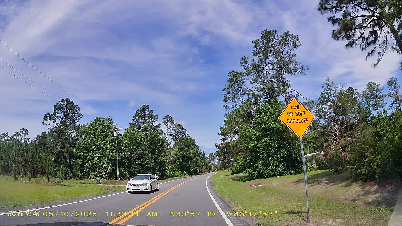 Shoulder warning sign beside westbound McMillan Road in Lowndes County, Georgia, seen from a car