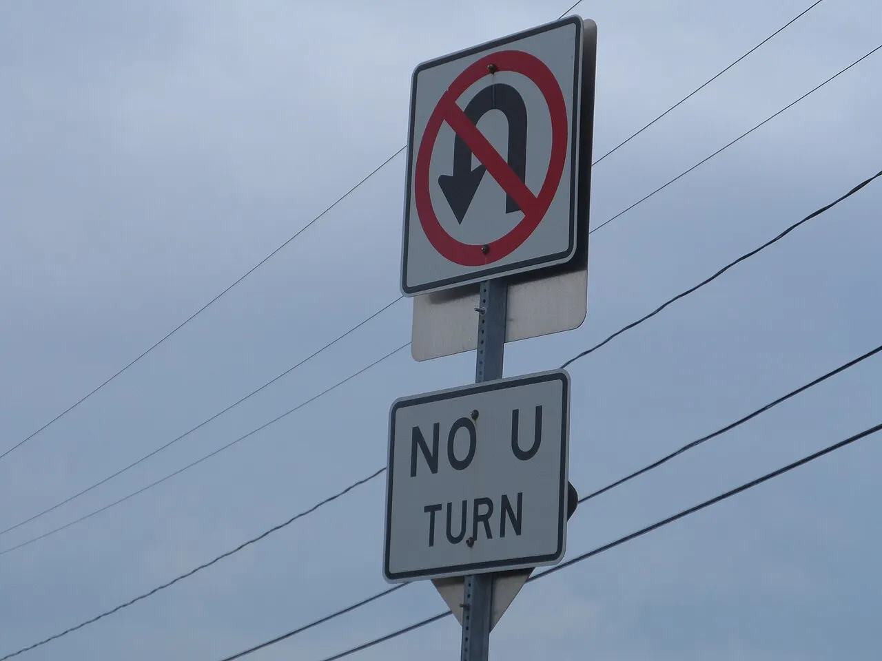 No U-Turn symbol sign with a NO U TURN word plaque mounted below it on a metal post