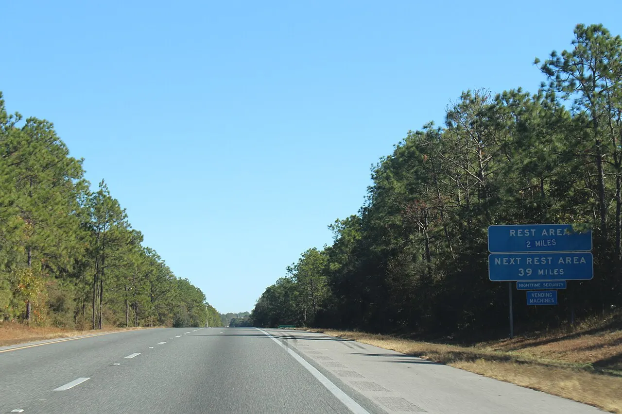 Blue REST AREA 2 MILES and NEXT REST AREA 39 MILES signs beside a four-lane interstate in Florida
