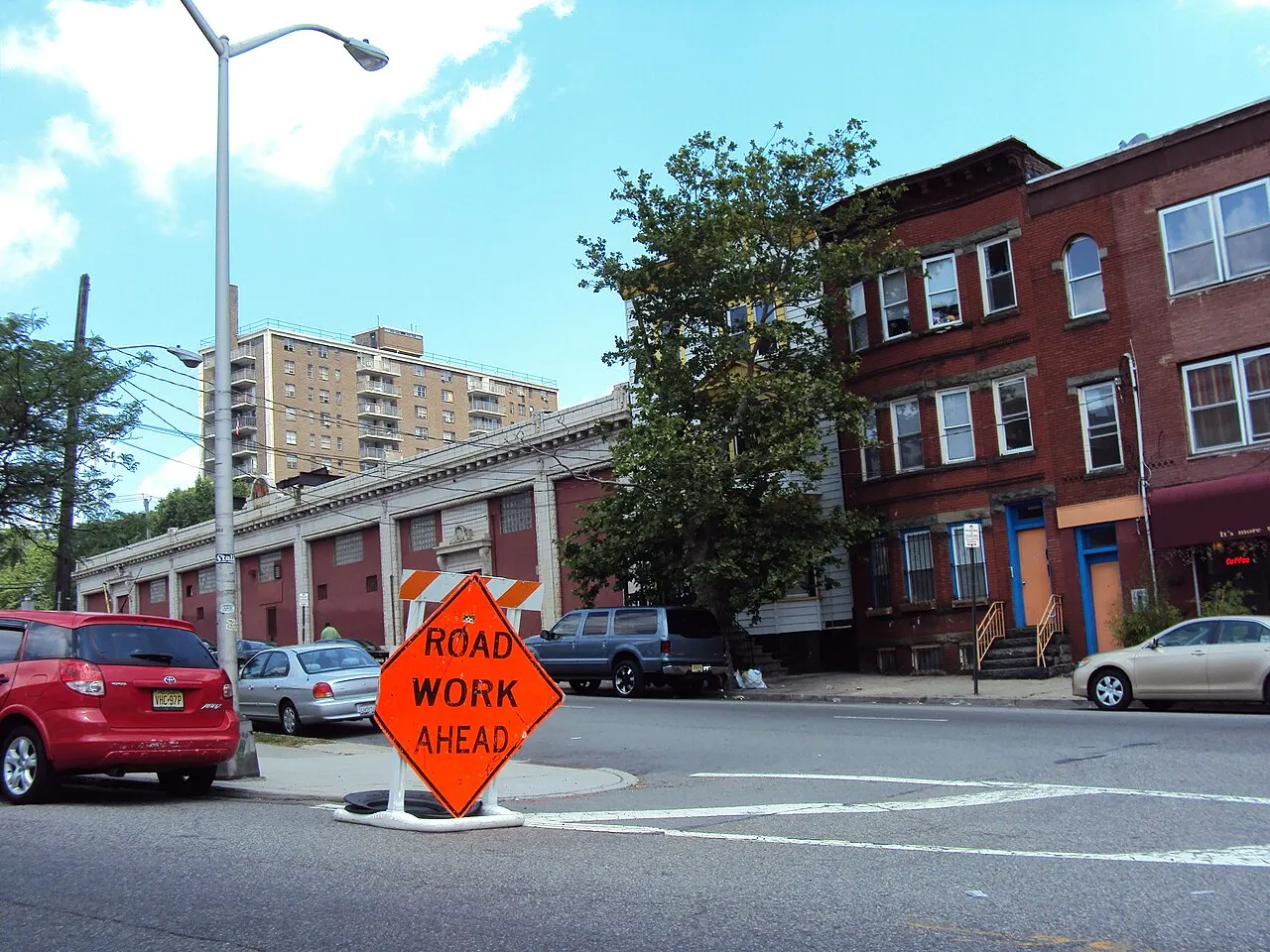 Orange diamond ROAD WORK AHEAD sign on a portable stand at a street corner in Newark, New Jersey