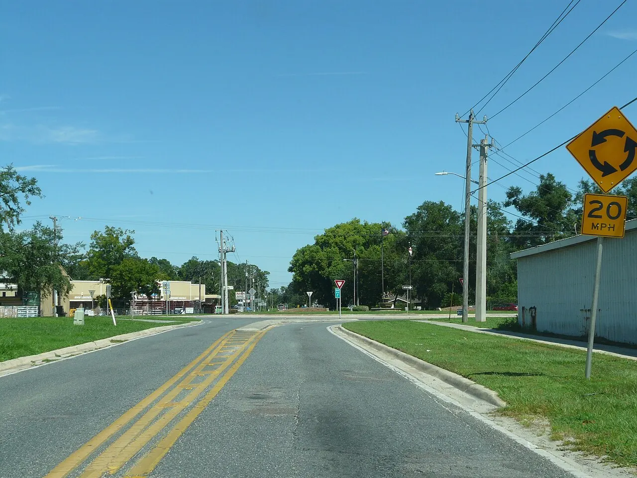 Yellow Circular Intersection warning sign with a 20 MPH advisory speed plaque on the approach to a roundabout in Live Oak, Florida