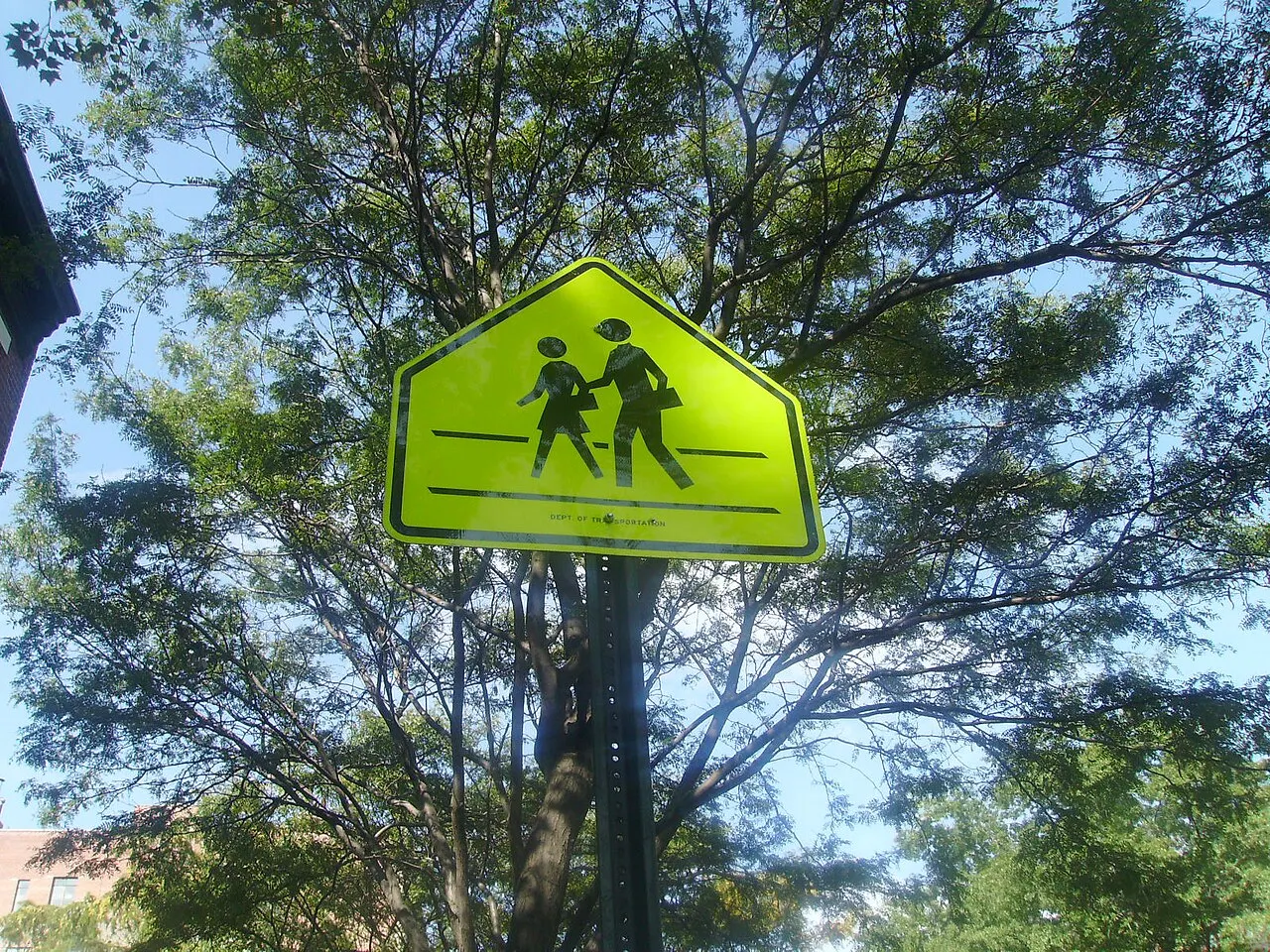 Fluorescent yellow-green five-sided School sign with two walking children on a pole in Manhattan
