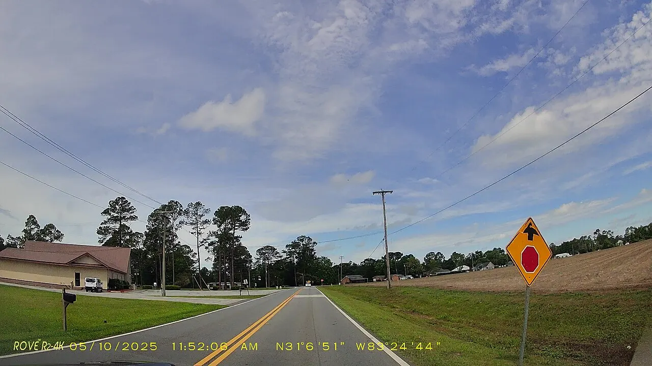 Yellow Stop Ahead warning sign with a red octagon symbol beside a rural two-lane road in Cook County, Georgia