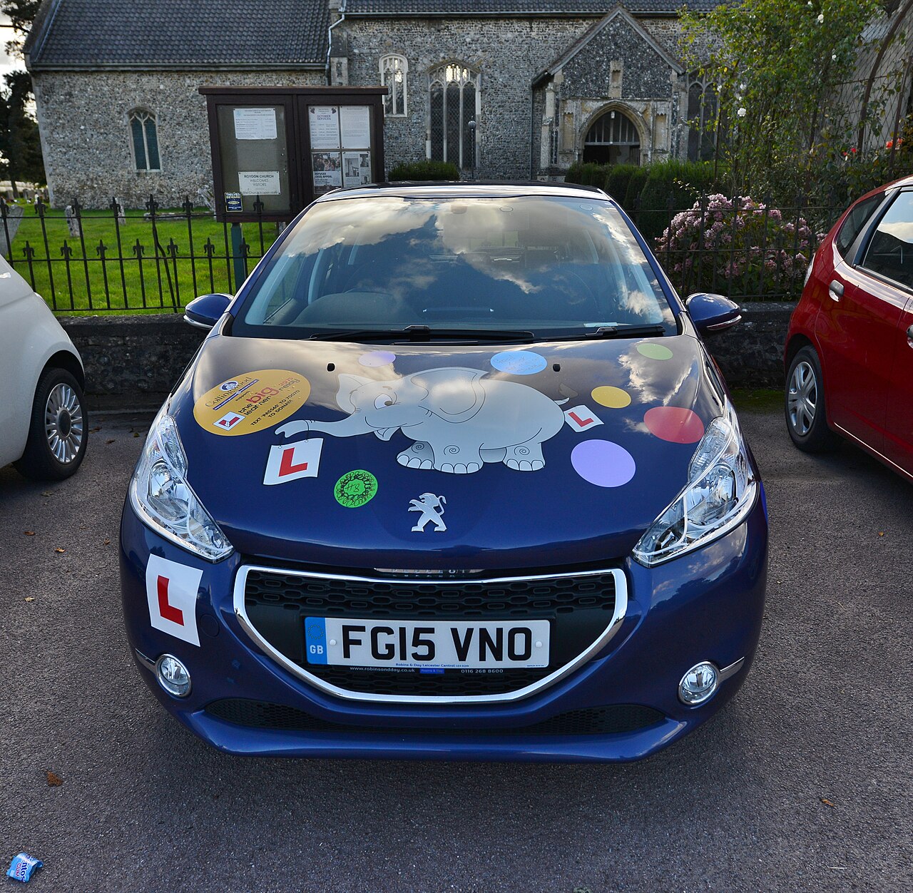 A learner driver's car parked on a quiet residential street in England, L plates displayed front and rear