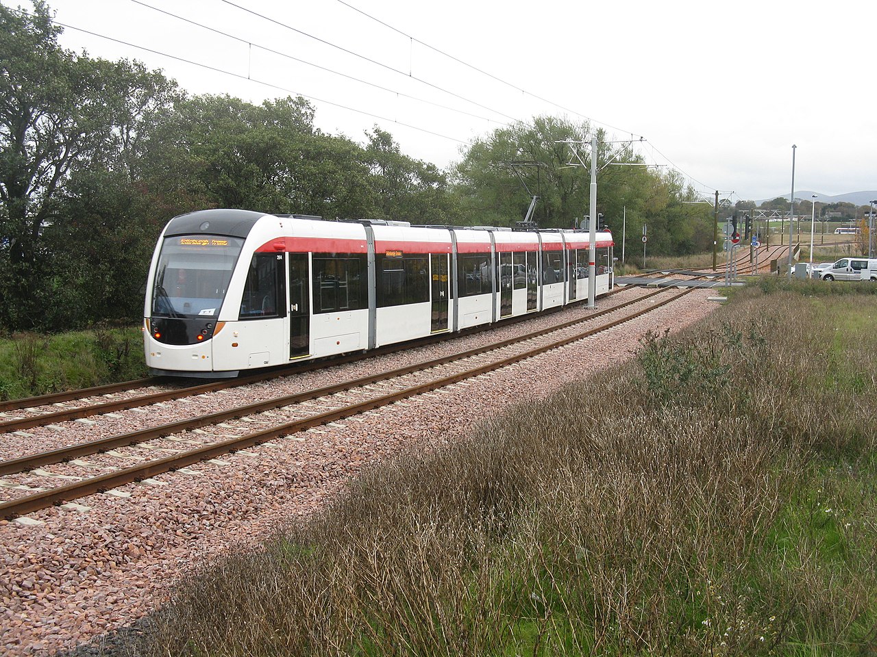 A Manchester-style tram crossing on a city street, the kind of fixture every Manchester test route revisits