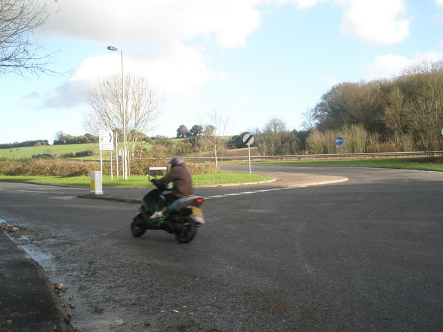 A moped rider approaching a UK roundabout
